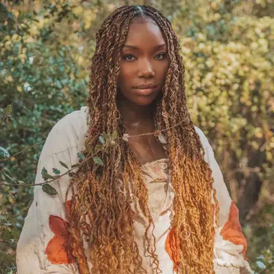 Brandy wears a long ombre twist hairstyle with blonde woven pieces and loose curly ends