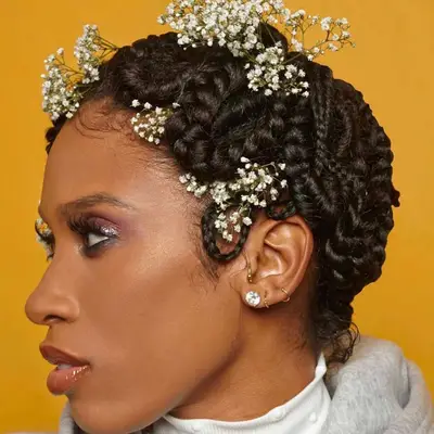 Side view of woman with twists arranged in a finger wave hairstyle with flowers