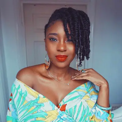 Woman wears a short twisted updo hairstyle with deep side part and red lipstick