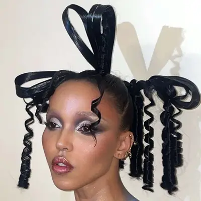 FKA Twigs with a sculptural bow updo hairstyle and glittery makeup