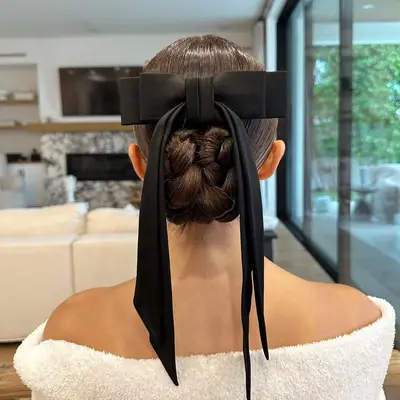 A model with a braided bun hairstyle accented with a bow