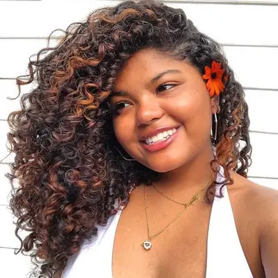 Woman with curly hair and copper bronze highlights