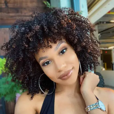 Woman with dark curls and subtle bronze highlights