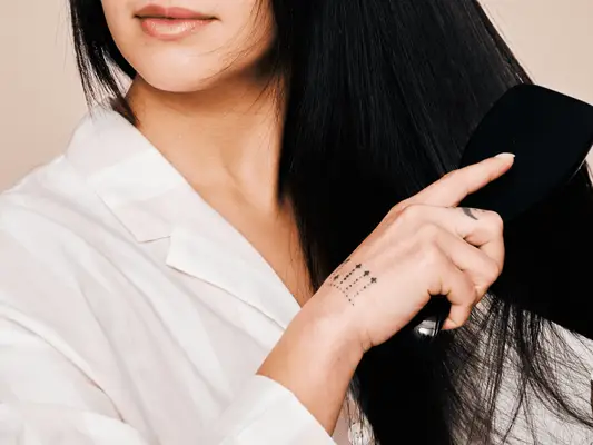 A woman running a hairbrush through her hair