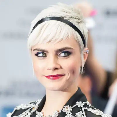 Cara Delevingne wears a silver-blonde pixie cut and black headband