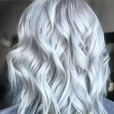Curled, cool-toned silver blonde hair viewed from back