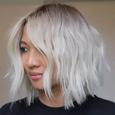 Woman with silver-blonde hair with dark shadowed roots