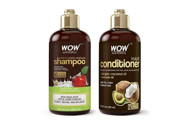 Apple cider vinegar shampoos from dpHue, SheaMoisture, and Wow Skinscience lined up on a marble counter