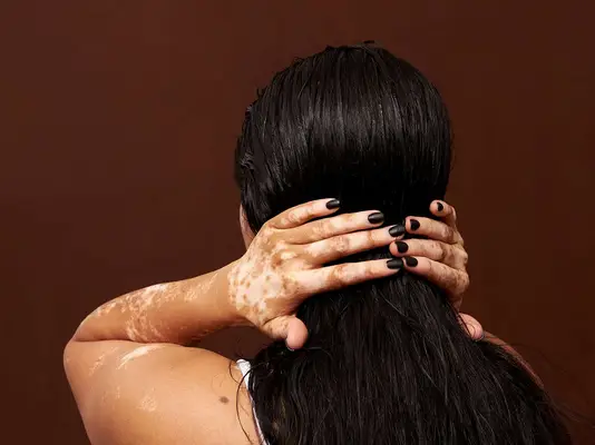 The back of a woman, isolated over studio brown background, hands in her hair
