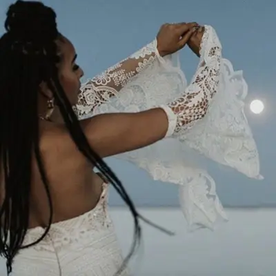 Woman with delicate white lace dress and long braids tied into half-up top knot