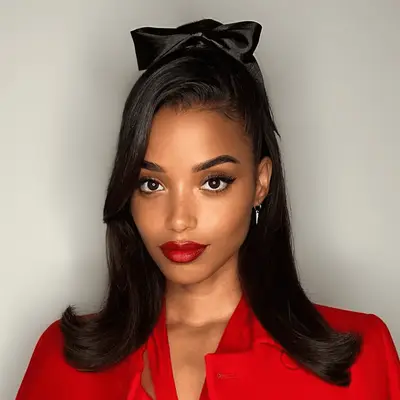 Justine Marjan with retro half-up half-down hair in black bow and red suit