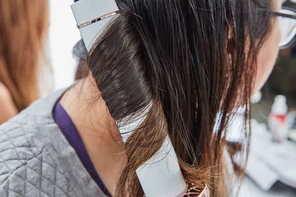 Closeup of a person curling a section of hair with the T3 1.25 Inch Twirl 360 Curling Iron
