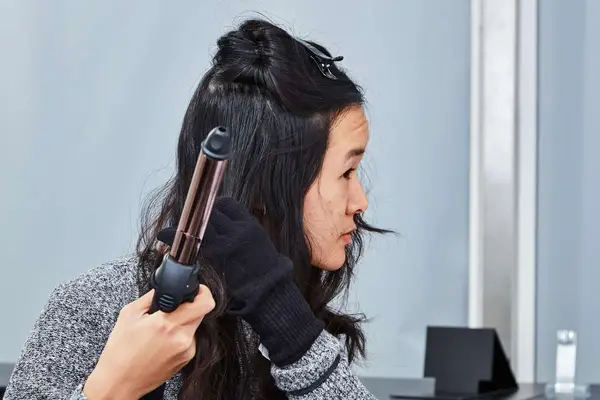 Person curling a section of their hair with the Prizm 1 Inch Wavy Professional Rotating Curling Iron