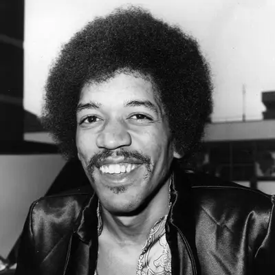 Jimi Hendrix wears a classic afro hairstyle and leather jacket