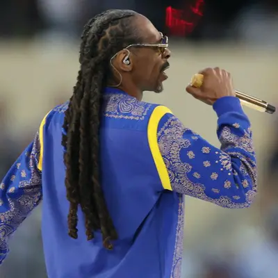 Snoop Dogg wears his signature dreadlocks and a blue paisley shirt