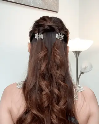 A woman picks an apple, wavy hair loosely held in a claw clip