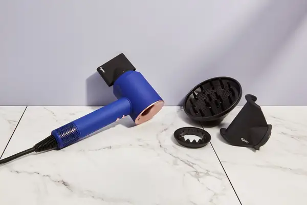 Dyson SuperSonic Hair Dryer and attachments displayed on marble surface