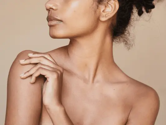 Close up of a models chest and shoulders, with short, brown curly at the nape of the neck.