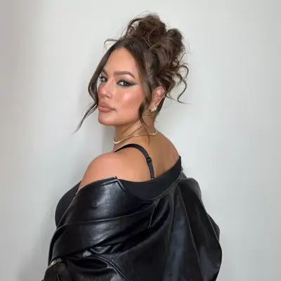 Ashley Graham wearing her hair in a messy bun updo