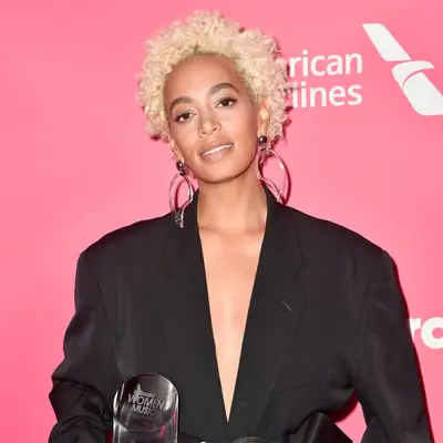 Solange posing at event wearing black blazer and platinum blonde tiny afro