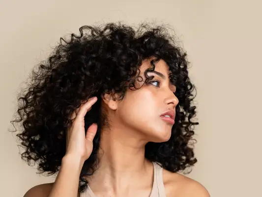 A woman with shiny, curly hair looking to the side