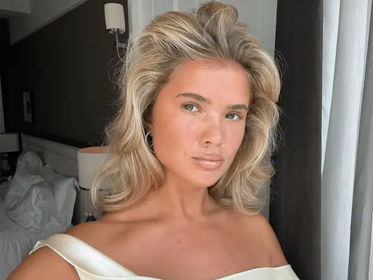 blonde woman with voluminous roots looking at camera