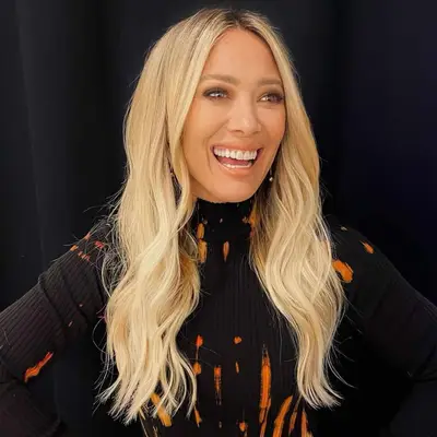 Hilary Duff wears a warm-toned platinum blonde curled blowout hairstyle