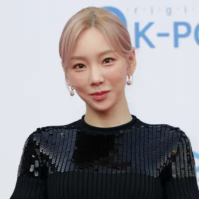 Taeyon wears a rose gold champagne blonde hair color and black sequined top