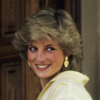 Princess Diana looks over her shoulder wearing teased bangs and face framing layers 