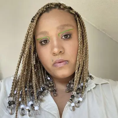Woman with beaded blonde box braids and green graphic eyeliner