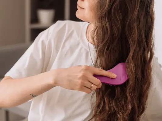 A woman combing the lengths of her wavy 2a hair