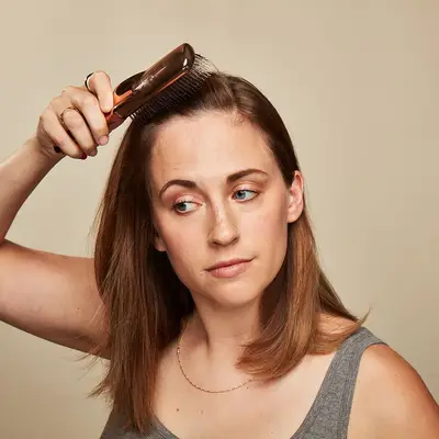 Model combing her hair in preparation for French braiding