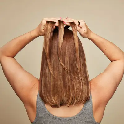 Model viewed from the back, holding three sections of hair