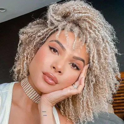 Doralys Britto wearing platinum blonde natural curls