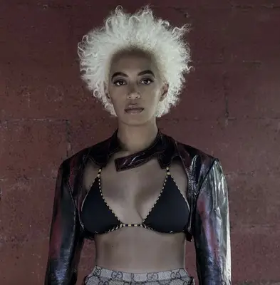 Solange Knowles with platinum bixie hair wearing black bikini top and leather jacket