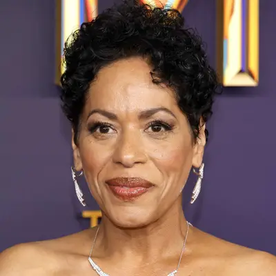 A person attending an event, posing against a decorative background