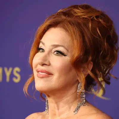 Lisa Ann Walter smiling at an event, wearing elegant earrings and with her hair styled up