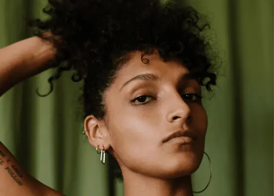 woman running hands through curly hair against green background