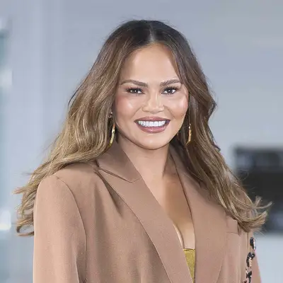 Chrissy Teigen wears ash-brown highlights and a taupe blazer
