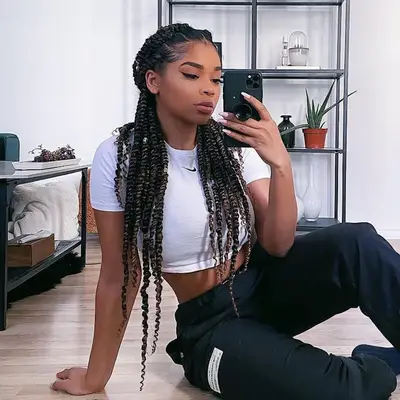 Woman takes mirror selfie with long box braids in half-up hairstyle