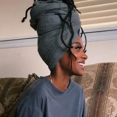 Side view of woman with locs piled high with gray wrap
