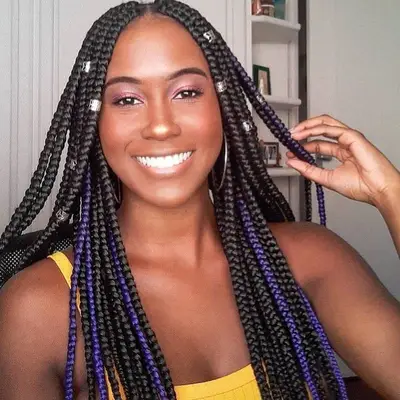 Woman with long box braids with purple accent braids and silver beads