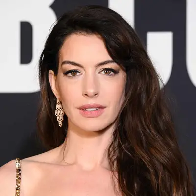 Anne Hathaway with accentuated downturned eyes and deep side-parted waves attends the Valentino Haute Couture Spring Summer 2023 show