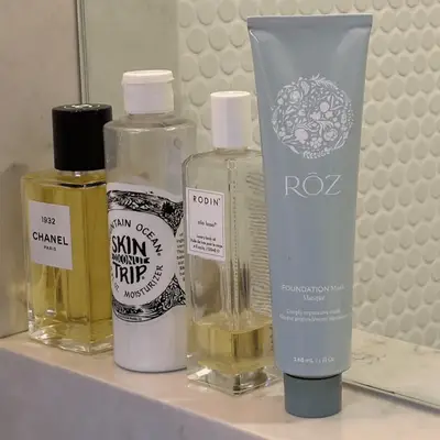 Products on a marble bathroom shelf, including Roz Hair Foundation Mask.