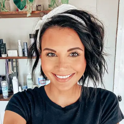 Person wears an asymmetrical bob hairstyle with a bandana headband