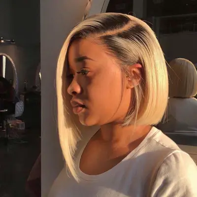 Person wears a platinum asymmetrical bob with natural dark roots