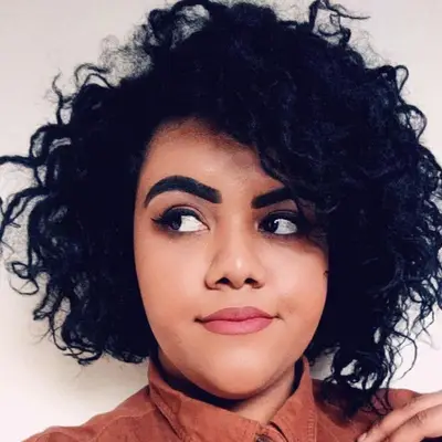 Person wears a voluminous curly asymmetrical bob