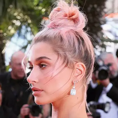Hailey Bieber wears a high bun with blonde to light pink ombré