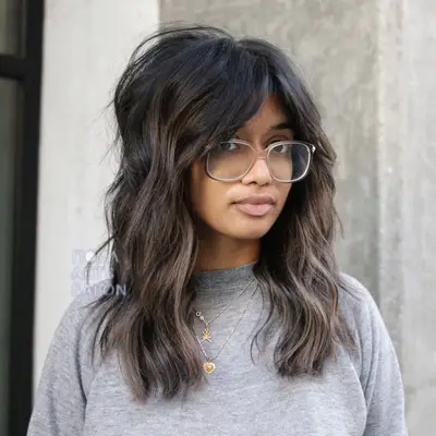 Person with medium-length tousled curls and bottleneck bangs