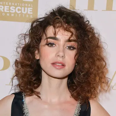 Lily Collins with a side-parted curly shag and wind-swept bangs at the 2017 Cannes Festival